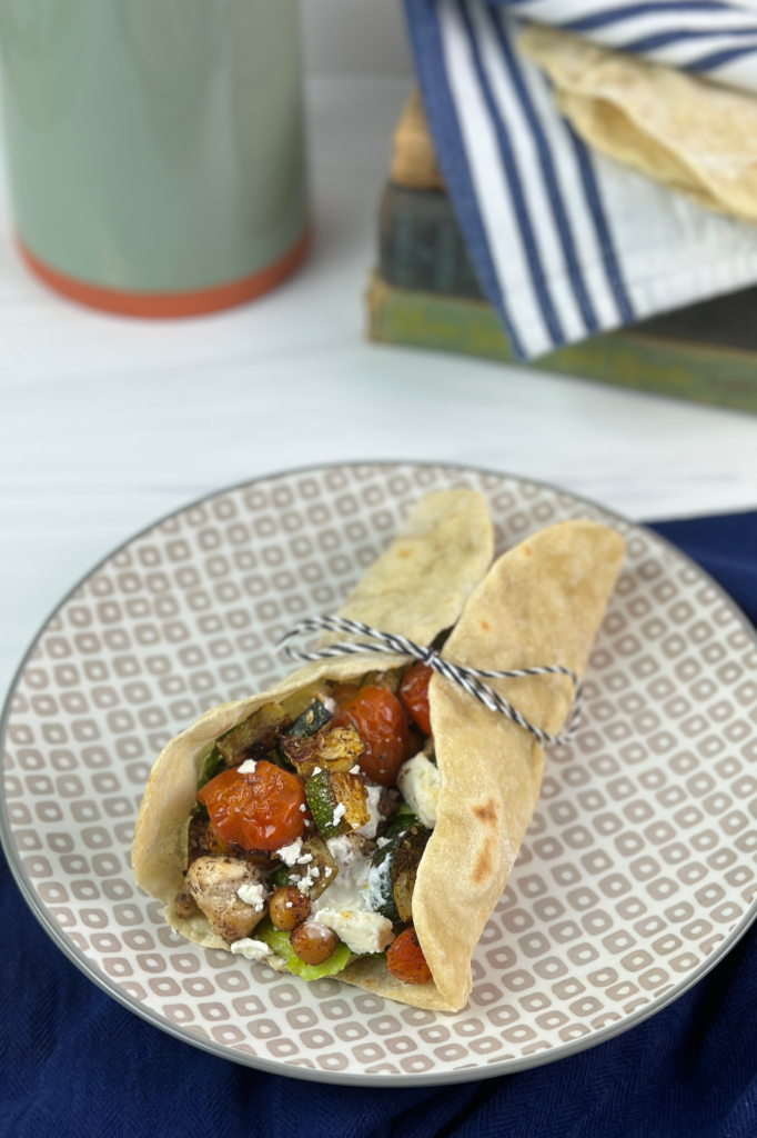 These Mediterranean Wraps feature a pita/tortilla stuffed with roasted vegetables, chickpeas, seasoned chicken, hummus, and a feta sauce.